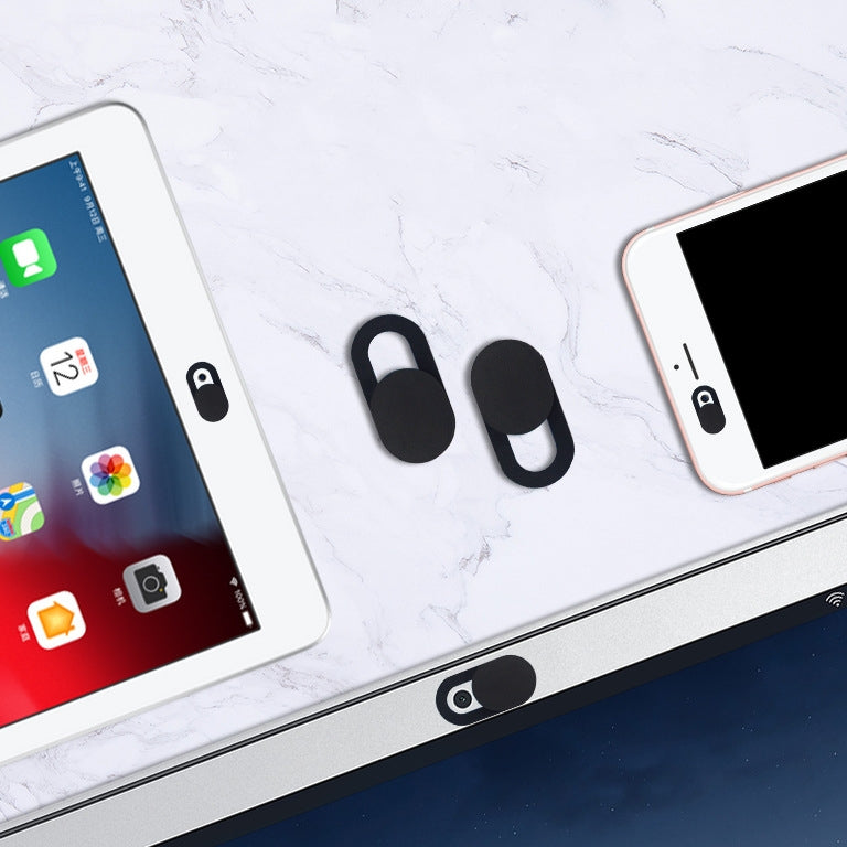 Two black oval webcam covers, one open and one closed, shown on a white surface with devices.